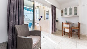 A room with a wicker chair, a wooden table, and a view through a glass door to an outdoor area. - Apartment In A Hotel 'Marina View, Sunny One Bedroom Pyr' with Shared Pool and Air Conditioning (Fuengirola)