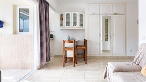 A room with a sofa, a dining table with chairs, a cabinet, and a wardrobe. - Apartment In A Hotel 'Marina View, Sunny One Bedroom Pyr' with Shared Pool and Air Conditioning (Fuengirola)