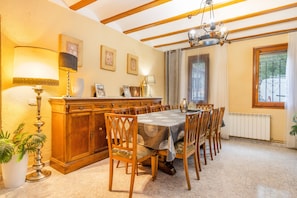 A dining room with a large table, wooden chairs, a cabinet, and a potted plant.