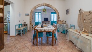 A dining area with a table set for four, a stone archway, and a view of the kitchen. - Apartment "Sara Home" with Sea View, Private Terrace & Wi-Fi (Portopalo di Capo Passero)