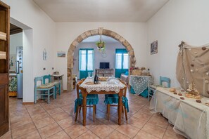Un coin repas avec une table dressée pour quatre personnes, une arche en pierre et une vue sur la cuisine.