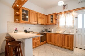 A kitchen with wooden cabinets, a countertop, a stove, and a sink.