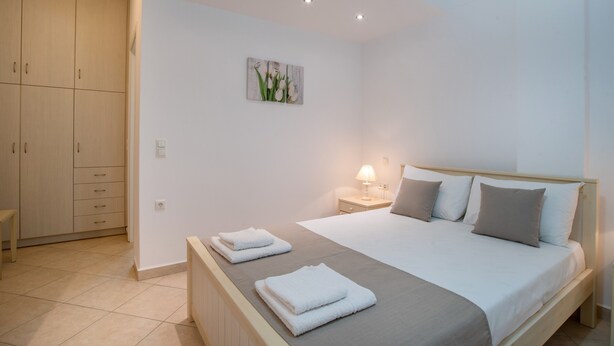Ein Schlafzimmer mit Bett, Nachttisch, Lampe und einem Bild an der Wand.