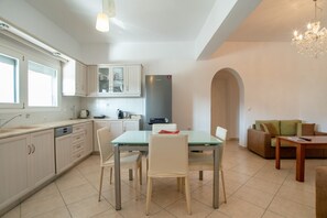 A modern kitchen with a dining area, a built-in oven, and a coffee machine.