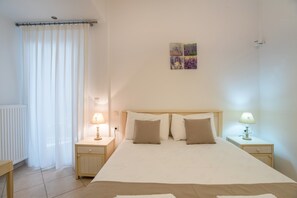 A bedroom with a bed, two bedside tables with lamps, a radiator, and a window with curtains.