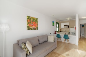A living room with a sofa, a coffee table, and a painting on the wall.