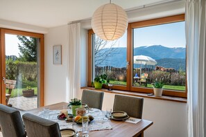 A dining area with a table set for four, large windows with a view of mountains, and a hanging paper lantern.