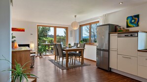Una cocina moderna con zona de comedor, suelo de madera y ventanas amplias.