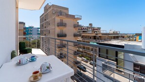 Varanda com mesa posta para chá, com vista para uma área residencial com vários edifícios e céu limpo.