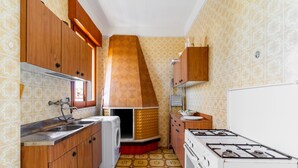 Uma cozinha compacta com armários de madeira, forno embutido, fogão a gás e ladrilhos no chão com padrão.