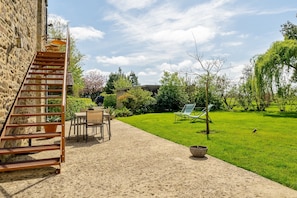 A stone staircase leading to a patio area with outdoor furniture and a grassy lawn.