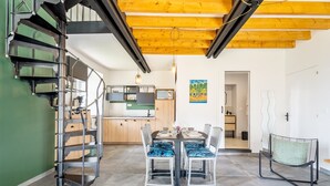 A modern interior with a staircase, dining table, chairs, and a kitchen area. - "Le Kerhuel d'Agnès" with private terrace, private garden and Wi-Fi (Plouasne)