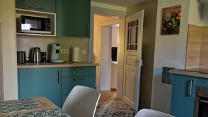 A kitchen with teal cabinets, a microwave, a coffee maker, and a patterned table. - Holiday Home "Chez Jeanne, Charming House" with Private Garden and Wi-Fi (Dossenheim-sur-Zinsel)