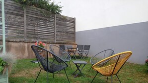 An outdoor patio with a table and chairs, a wooden fence, and a concrete wall. - Holiday Home "Chez Jeanne, Charming House" with Private Garden and Wi-Fi (Dossenheim-sur-Zinsel)