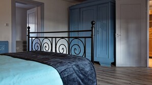 A bedroom with a bed, a wardrobe, and a door. - Holiday Home "Chez Jeanne, Charming House" with Private Garden and Wi-Fi (Dossenheim-sur-Zinsel)