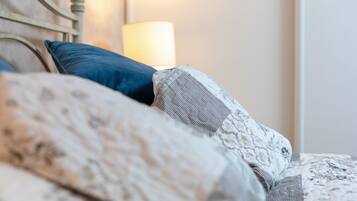 Un lit avec une literie et des oreillers à motifs, une tête de lit et une lampe de chevet.