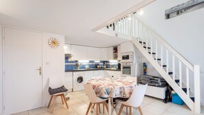 A modern kitchen with a dining table, chairs, and a staircase. - Naturist holiday home 'Résidence Naturiste Eden' with sea view, private terrace, and Wi-Fi (Leucate)