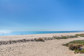 En sandstrand med et træhegn og lidt grønt.