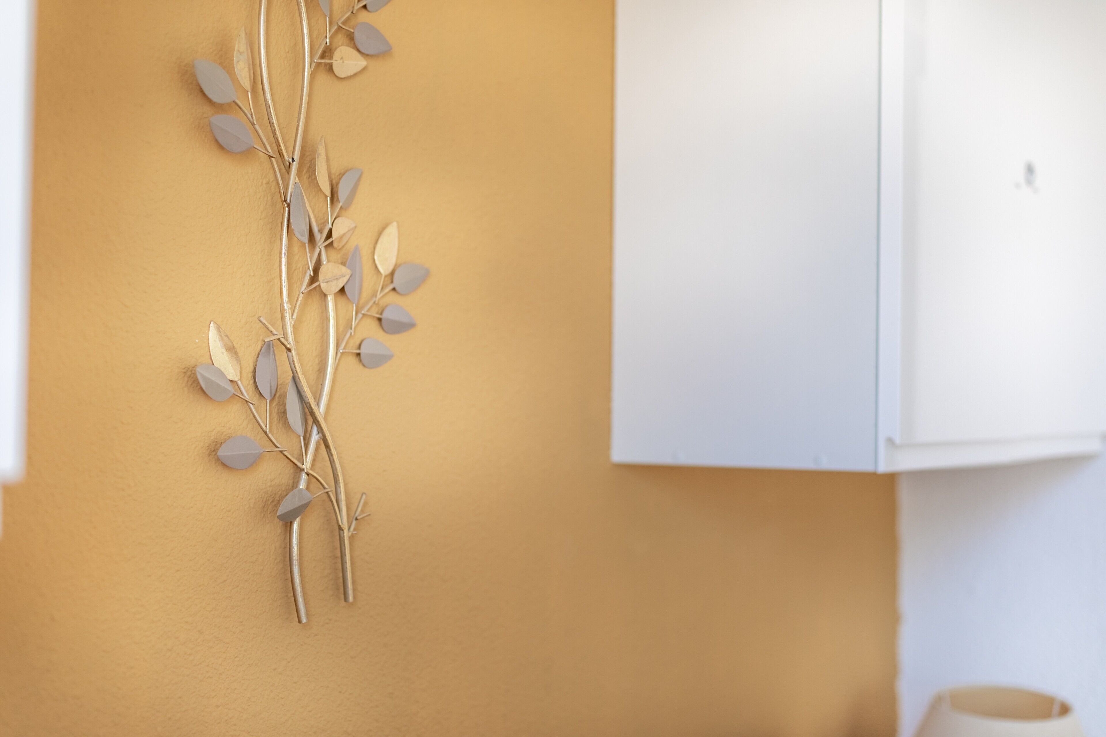 Decorazione a forma di ramo fissata al muro, su fondo giallo.
