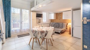 A modern kitchen with a dining table, white cabinets, and a built-in oven. - Naturist holiday home 'Résidence Naturiste Eden' with sea view, private terrace, and Wi-Fi (Leucate)