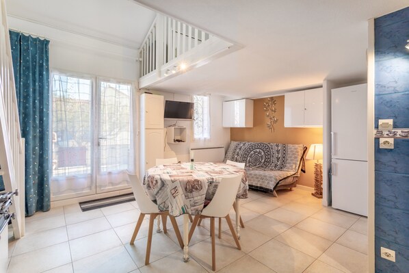 A modern kitchen with a dining table, white cabinets, and a built-in oven.
