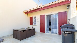 An outdoor patio with a pool table, a barbecue grill, and a door leading to a covered area. - Naturist holiday home 'Résidence Naturiste Eden' with sea view, private terrace, and Wi-Fi (Leucate)