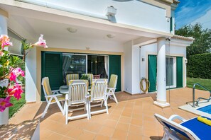 A covered patio with a table and chairs, a pool, and a view of the greenery. - Villa "Mng Elliott 50" with Private Pool & Wi-Fi (Vale do Lobo)