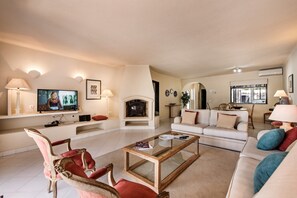 Una sala de estar con chimenea, televisor, sofá y una mesa de centro.