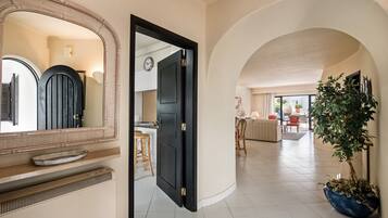 An open doorway leading to a living area with a dining table, chairs, and a potted plant.