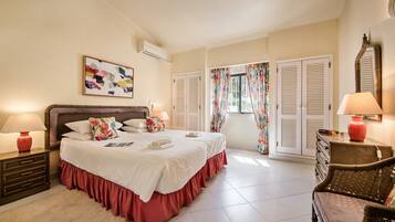A bedroom with a bed, two bedside tables with lamps, a dresser, a chair, and a window with curtains.