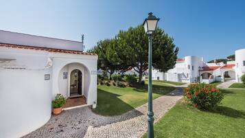 A courtyard with cobblestone paths, white buildings, and a lamppost.