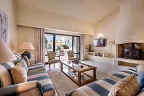 A living room with striped sofas, a coffee table, a fireplace, and a TV on the wall. - Villa "Mng Elliott 13" with Private Pool & Wi-Fi (Vale do Lobo)