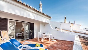 Un patio con due poltrone blu, un tavolo e una sedia.
