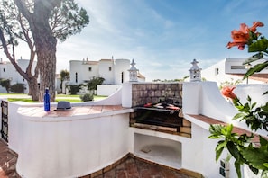 A barbecue grill in a white-walled outdoor area with a tree and a view of neighboring buildings. - Villa "Mng Elliott 72" with Private Pool & Wi-Fi (Vale do Lobo)