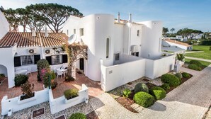Un edificio bianco con tetto in tegole, un cortile con posti a sedere e un giardino curato.