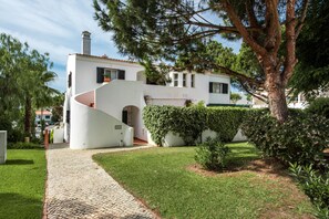 Una casa moderna con una original escalera curva, un camino de entrada pavimentado y un jardín cuidado.