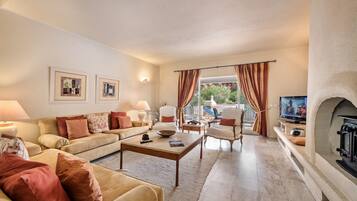 Ein Wohnzimmer mit einer Couch, Sesseln, einem Couchtisch, einem Fernseher und einem Kamin.