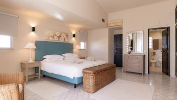 Een slaapkamer met een bed, nachtkastjes, een kaptafel en een zichtbare badkamer door een open deur.