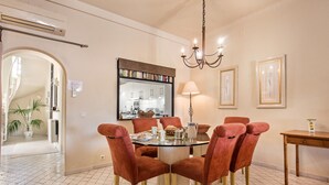A dining area with a round glass table, red upholstered chairs, a chandelier, and framed artwork on the walls. - Villa 'Mng Elliott37' with Private Pool, Wi-Fi and Air Conditioning (Vale do Lobo)