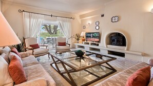 A living room with a fireplace, a television, and a sofa. - Villa 'Mng Elliott37' with Private Pool, Wi-Fi and Air Conditioning (Vale do Lobo)