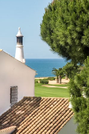 Un bâtiment situé sur la côte, doté d’un phare, d’un toit recouvert de tuiles et offrant une vue sur la mer.