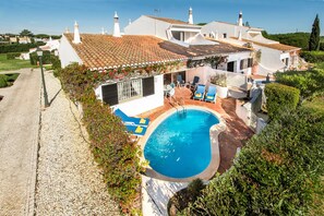 A house with a swimming pool, outdoor seating, and a garden.