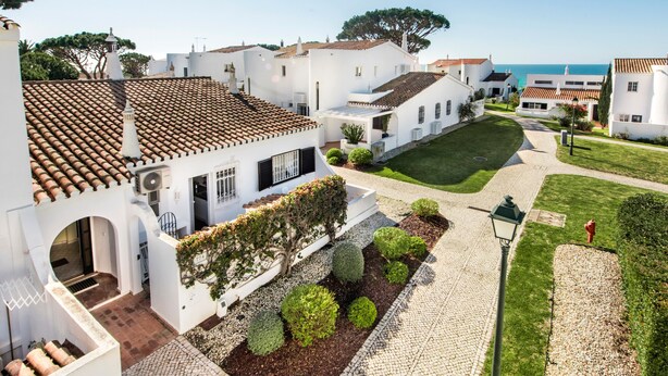 A white building with a tiled roof, a paved courtyard, and a view of the sea. - Villa "Mng Elliott 74" with Private Pool and Wi-Fi (Vale do Lobo)
