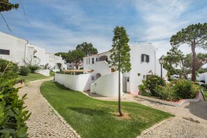 A white building with a paved pathway and greenery.