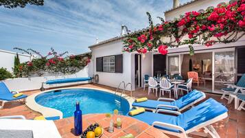 A pool area with lounge chairs, a table with drinks, and a book titled 'The Affair'.
