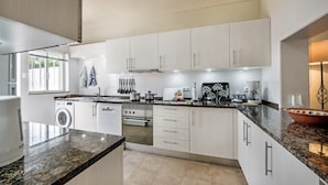 Eine moderne Küche mit weißen Schränken, Granit Arbeitsplatten, einem eingebauten Backofen und einer Waschmaschine.