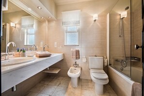 A modern bathroom with a large sink, bidet, toilet, and glass-enclosed shower.