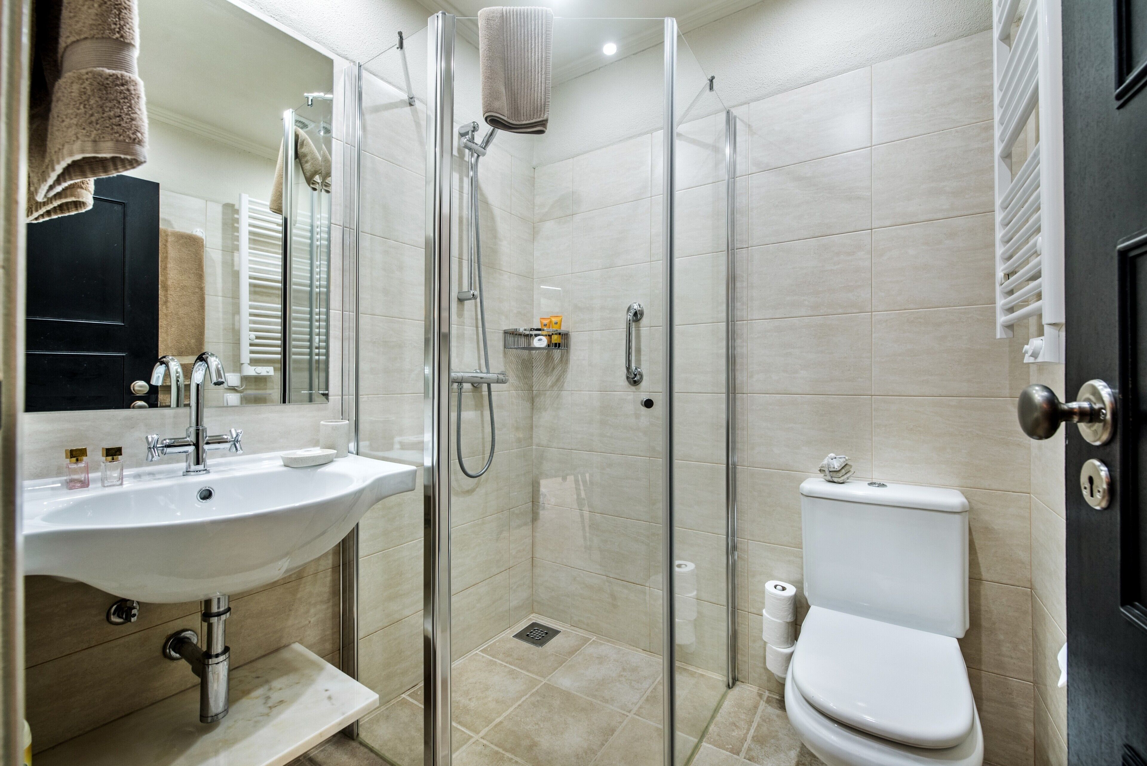 Een badkamer met een douchecabine van glas, een wastafel, een toilet en een spiegel.