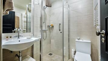 Een badkamer met een douchecabine van glas, een wastafel, een toilet en een spiegel.