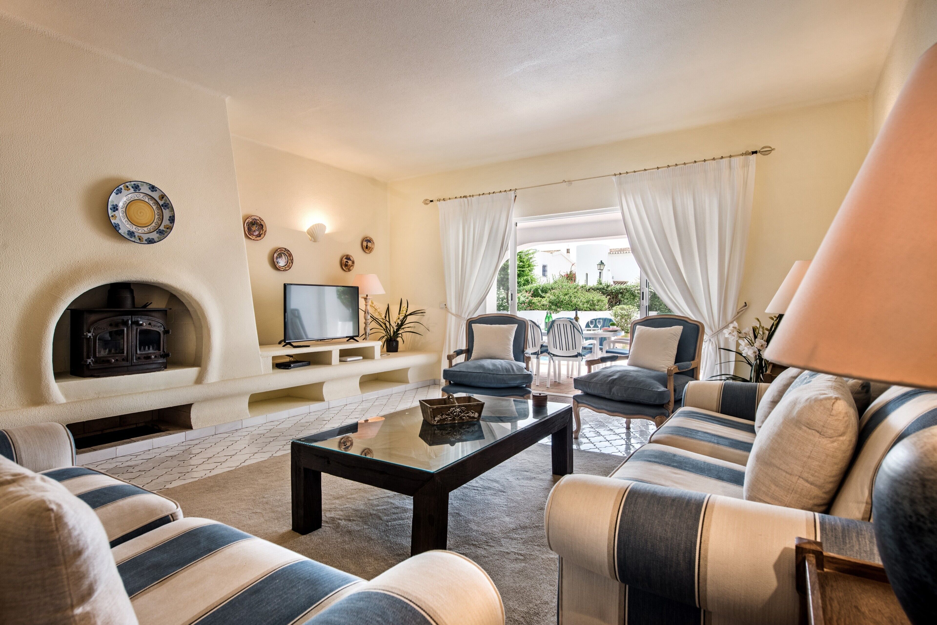 Un salon avec une cheminée, un canapé, des fauteuils et un téléviseur.